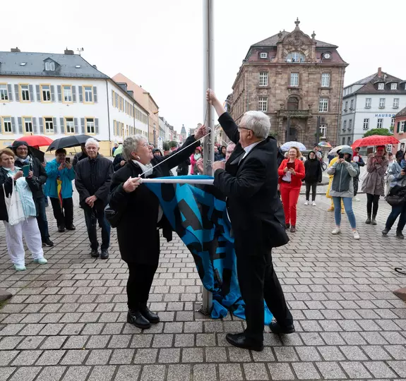 Für Demokratie, gegen Extremismus: Kirchenpräsidentin Wüst und Bischof Wiesemann hissen zum Start der Kampagne "Aufstehen für" eine Flagge vor dem Dom. Foto: Klaus Landry