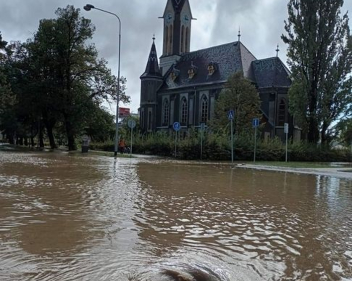 Ein brauner Fluss fließt vor einer Kirche.