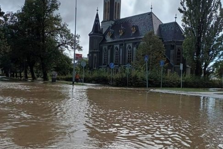 Ein brauner Fluss fließt vor einer Kirche.