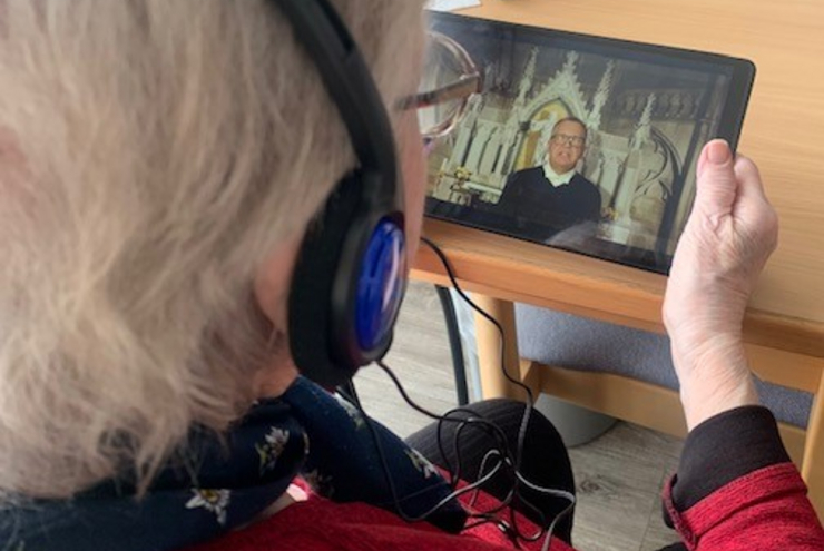 Eine Seniorin schaut eine Video-Andacht auf dem Tablet.