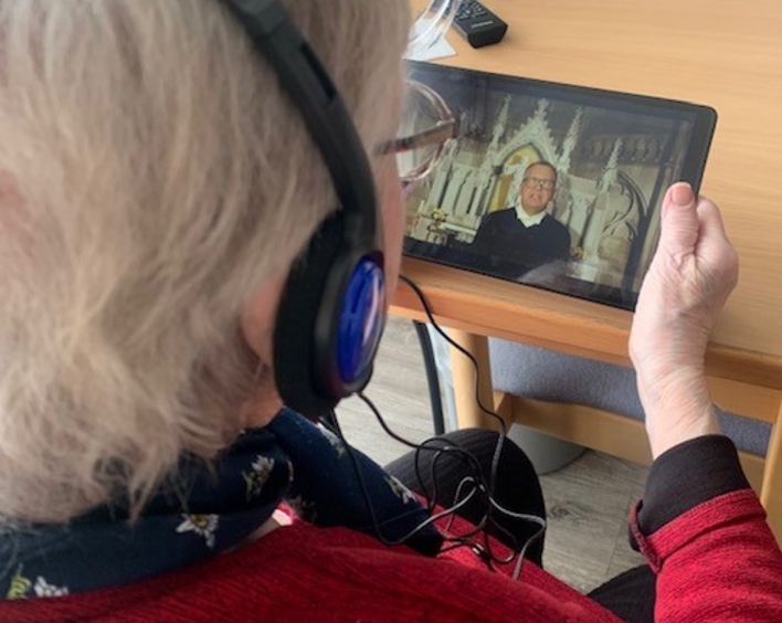 Eine Seniorin schaut eine Video-Andacht auf dem Tablet.