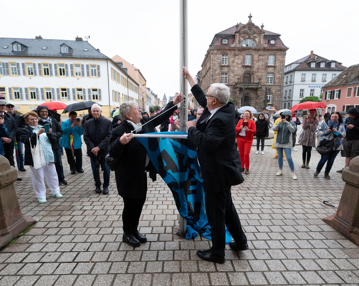Für Demokratie, gegen Extremismus: Kirchenpräsidentin Wüst und Bischof Wiesemann hissen zum Start der Kampagne "Aufstehen für" eine Flagge vor dem Dom. Foto: Klaus Landry