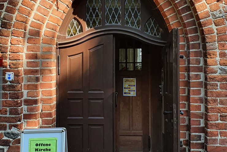 Geöffnetes Kirchenportal einer Backsteinkirche auf Rügen.