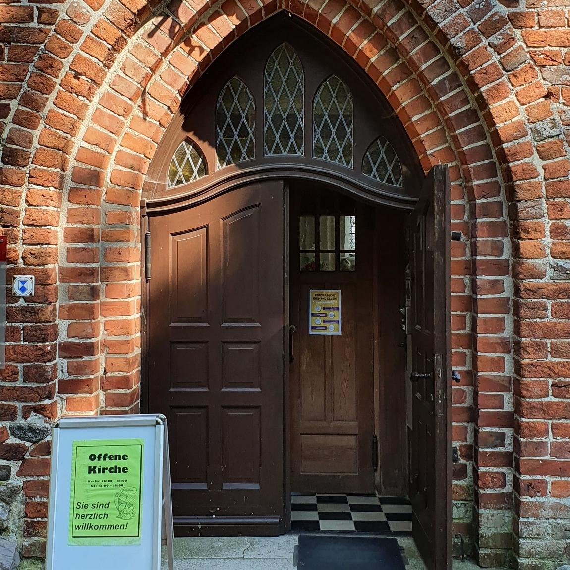 Geöffnetes Kirchenportal einer Backsteinkirche auf Rügen.