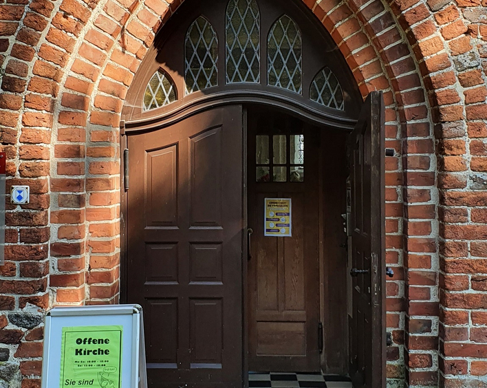 Geöffnetes Kirchenportal einer Backsteinkirche auf Rügen.