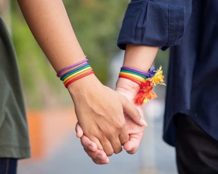 Händchen halten mit der Regenbogenflagge nachempfundenen Armbändern