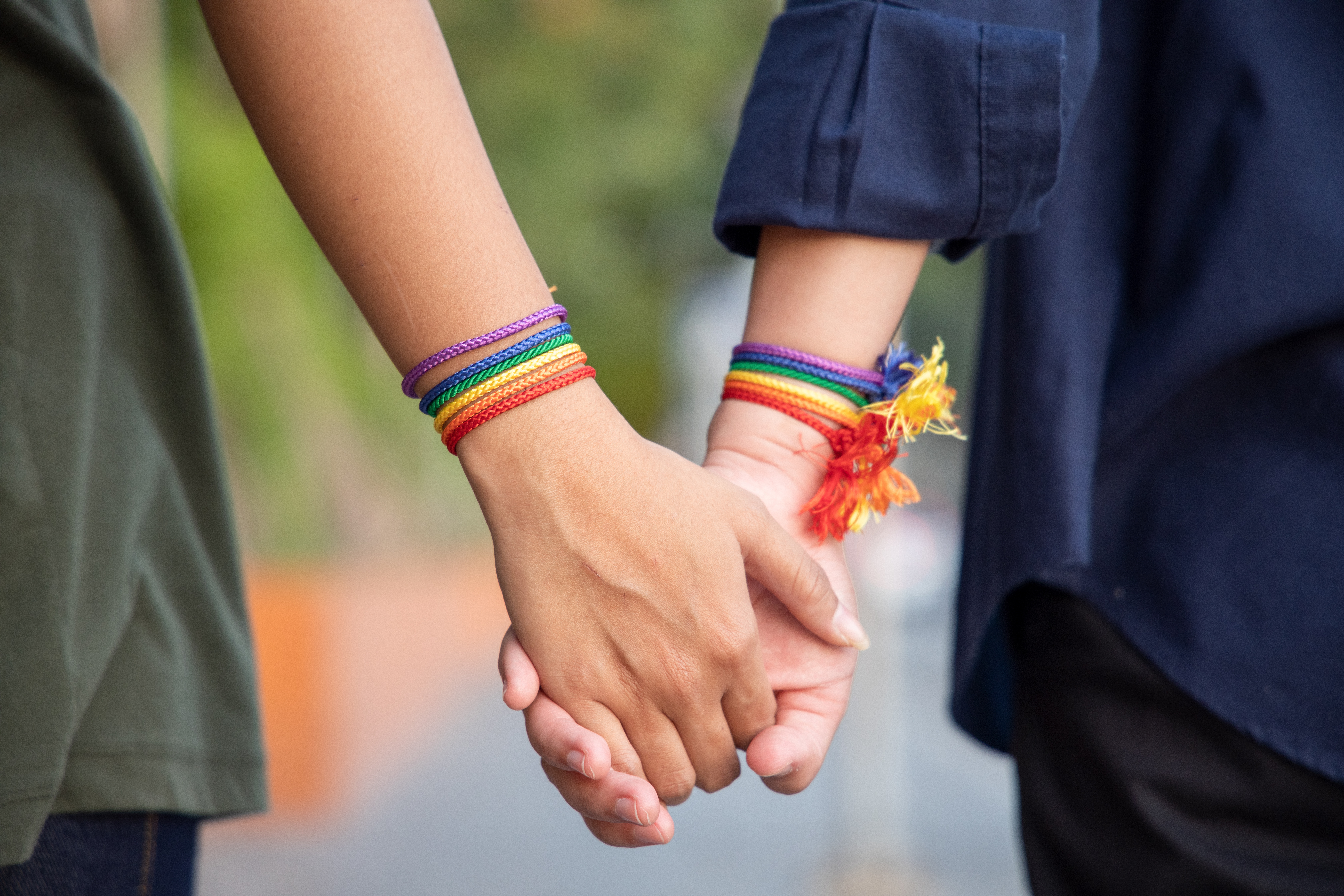 Händchen halten mit der Regenbogenflagge nachempfundenen Armbändern