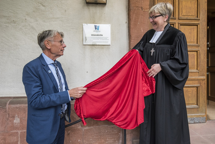 Aus "Kleiner Kirche" wird "Unionskirche": Der Kaiserslauterer Oberbürgermeister Klaus Weichel und Dekanin Dorothee Wüst enthüllen das neue Schild.