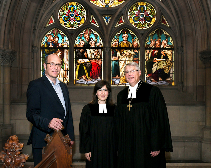 Vor dem Pfingstfenster der Speyerer Gedächtniskirche: Kirchenmusikdirektor Robert Sattelberger, Pfarrerin Lena Vach und Kirchenpräsident Christian Schad (v.l.).