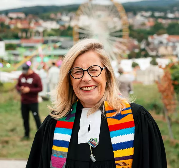 Pfarrerin Diemut Meyer im Talar vor dem Wurstmarkt-Panorama