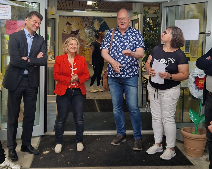 Eine Gruppe MEnschen steht im Halbkreis vor der Eingangstür einer Kita