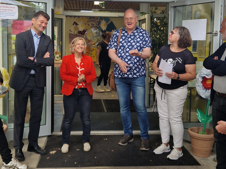 Eine Gruppe MEnschen steht im Halbkreis vor der Eingangstür einer Kita