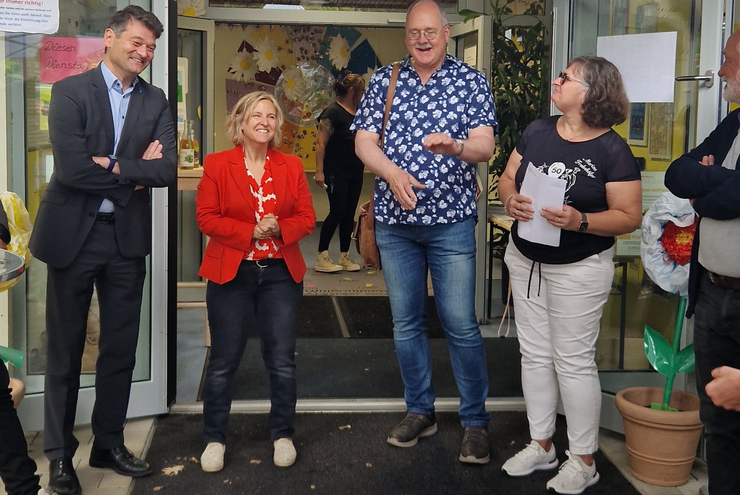 Eine Gruppe MEnschen steht im Halbkreis vor der Eingangstür einer Kita