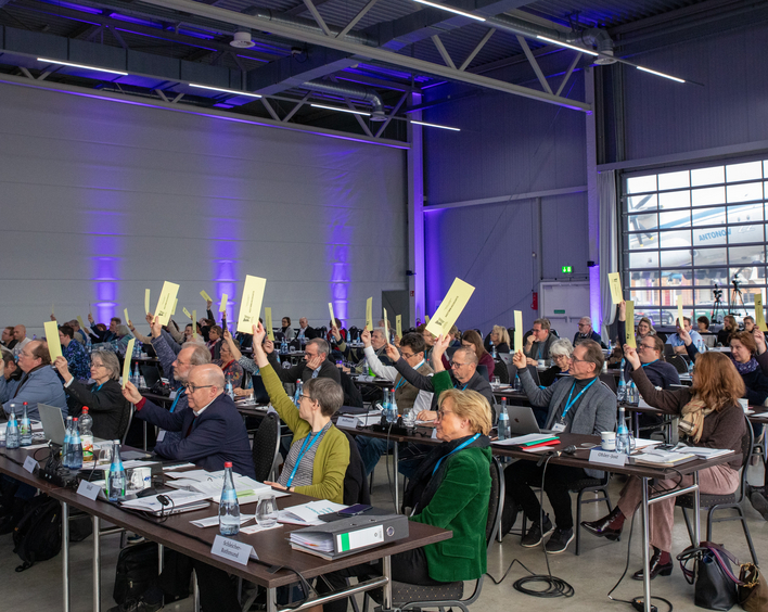 Menschen heben einen Stimmzettel in die Höhe