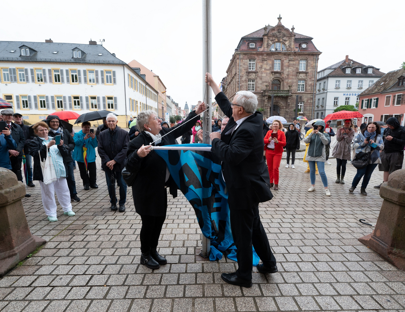 Vor dem Dom zu Speyer: Kirchenpräsidentin Dorothee Wüst und Bischof Karl-Heinz Wiesemann hissen die Fahne zur Aktion Aufstehen für Menschenwürde.