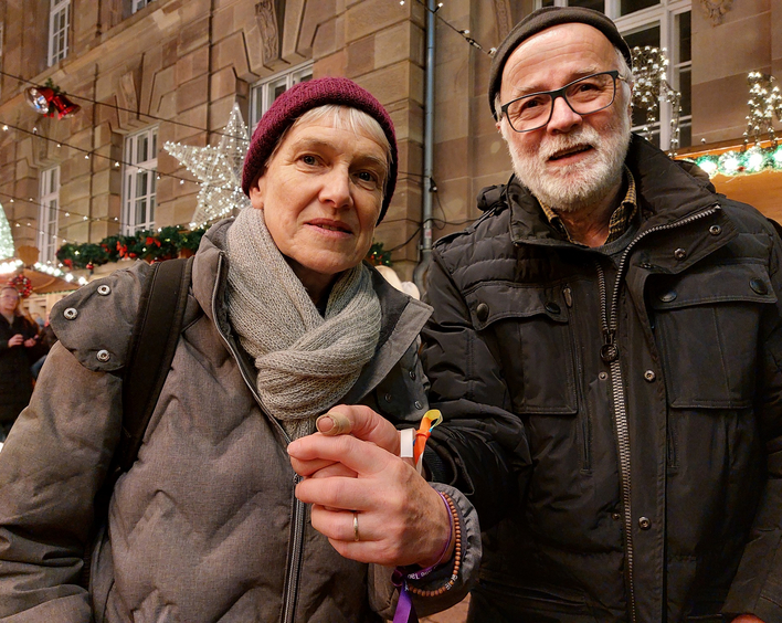 Mary und Werner Kunz: An der Pyramide auf dem Speyerer Weihnachtsmarkt ließen sie sich den Weihnachtssegen und Segensbändchen für das Handgelenk geben. Foto: Lore Dohrenbusch