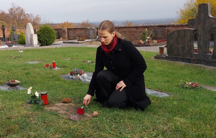 Erfüllt den Wunsch einer Angehörigen: Pfarrerin Jutta Fang legt auf dem Friedhof eine Rose aufs Urnengrab. Foto: Dohrenbusch